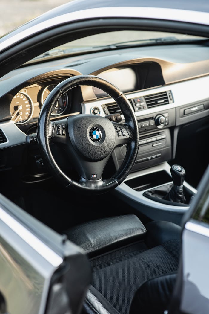 Close-up of sleek car interior featuring a steering wheel and dashboard controls.